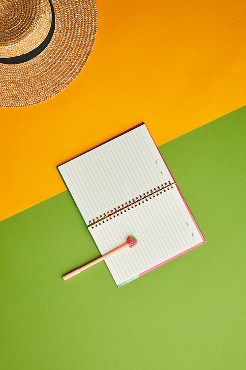 Bright color pop composition of straw hat and opened planner over graphic Tropical background, copy space