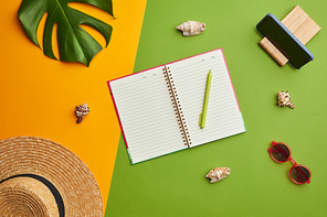 Bright color pop composition of straw hat and opened planner over graphic tropical background with vacation vibes, copy space