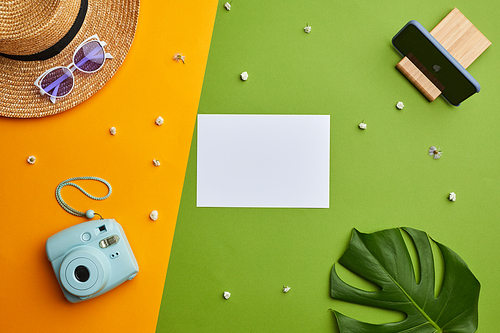 Bright color pop composition of blank white paper and instant camera over graphic tropical background with vacation vibes , copy space