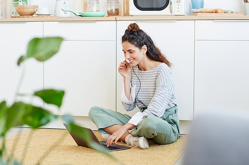 Young Caucasian woman wearing casual clothes sitting relaxed on floor using her laptop computer