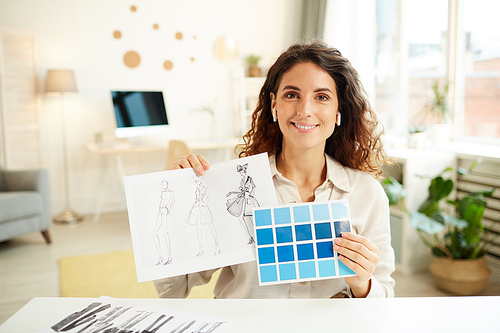 Female clothes designer demonstrating sketches and blue colour palette on camera, horizontal medium portrait
