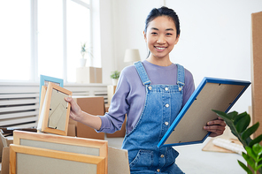 Portrait of young Asian woman packing boxes and smiling at camera excited for moving to new house or apartment, copy space
