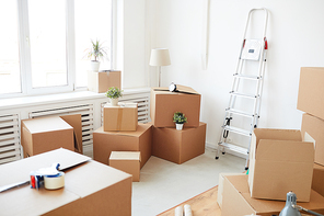 Wide angle background of stacked cardboard boxes in empty white room, moving, relocation and house decor concept, copy space