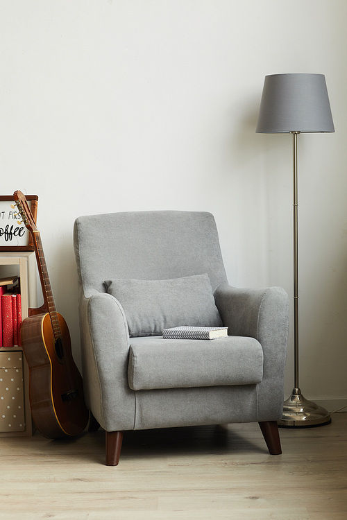 Vertical image of cozy grey armchair next to white wall in male design interior, copy space