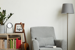 Background image of cozy modern interior with minimal decor items and grey armchair against white wall, copy space above