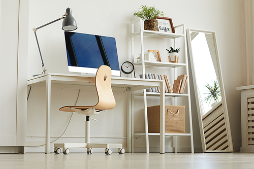 Low angle view at all-white home office workplace with wooden chair and modern computer on desk, copy space