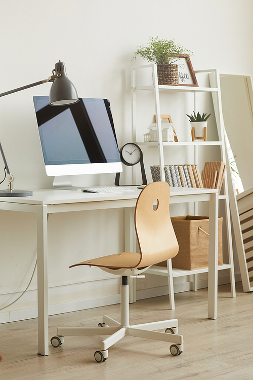 Vertical background image of cozy home office workplace with minimal design, focus on wooden char against computer desk in foreground, copy space