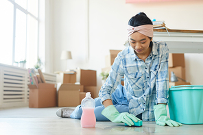 Full length portrait of happy Asian woman cleaning floor in new house or apartment after moving in, copy space