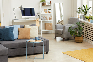 Background image of modern studio apartment interior in grey and white colors and focus on sofa with decor elements, copy space
