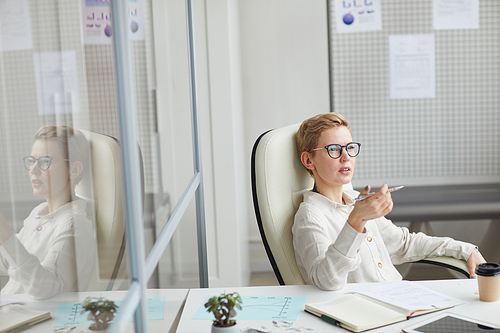 High angle view at modern short haired woman wearing glasses sitting in big office chair at work, female boss concept, copy space