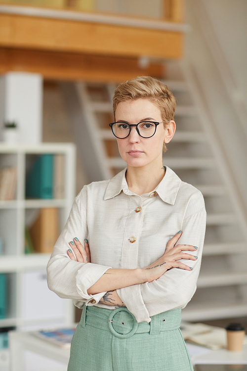 Waist up portrait of confident businesswoman  while standing with arms crossed in office