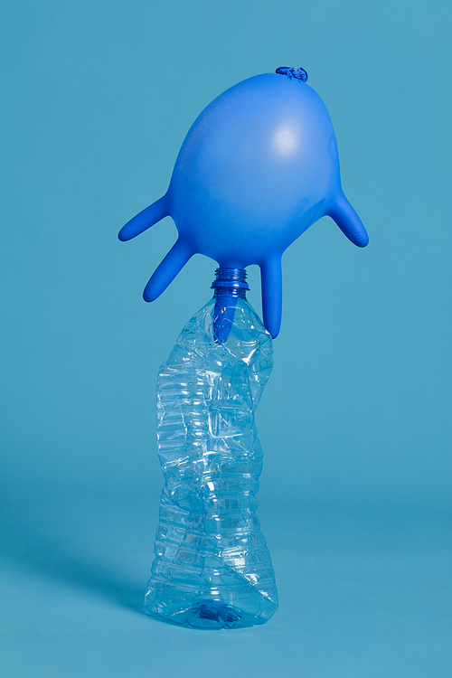 Full length view at discarded plastic bottle shot in studio against blue background, waste sorting and recycling concept