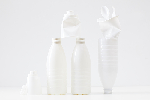Minimal composition of white plastic bottles and items on white background, waste sorting and recycling concept