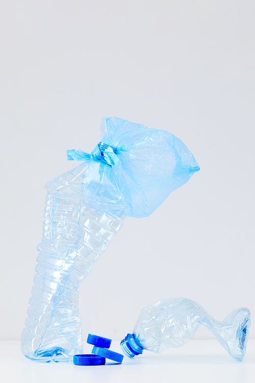 Minimal composition of discarded blue plastic bottles on white background, waste sorting and recycling concept, copy space