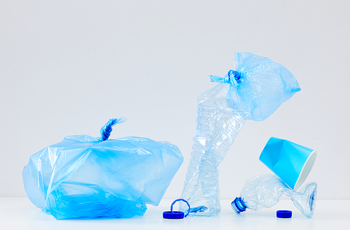 Minimal composition of discarded blue plastic items on white background, waste sorting and recycling concept, copy space