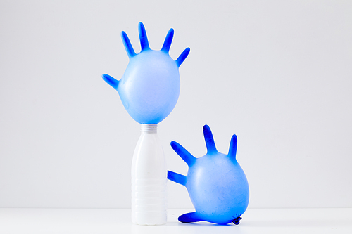 Minimal composition of discarded plastic items on white background, focus on blue rubber gloves, waste sorting and recycling concept, copy space