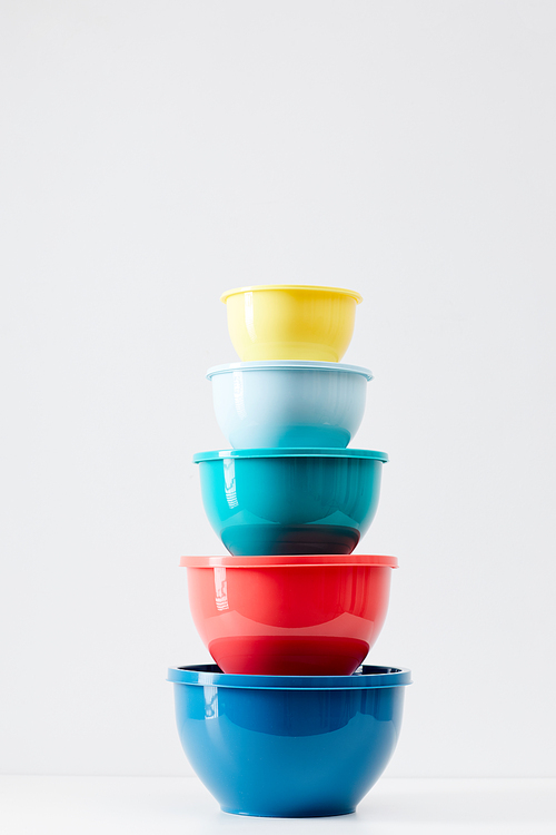 Minimal composition of colorful food containers stacked in row on white background, plastic storage and recycling concept, copy space