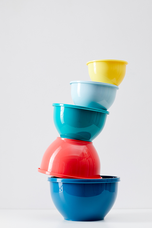 Minimal composition of colorful food containers stacked on white background, plastic storage and recycling concept, copy space