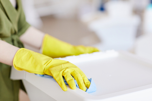 Close up of unrecognizable woman wearing yellow rubber gloves while cleaning plastic containers at home, copy space
