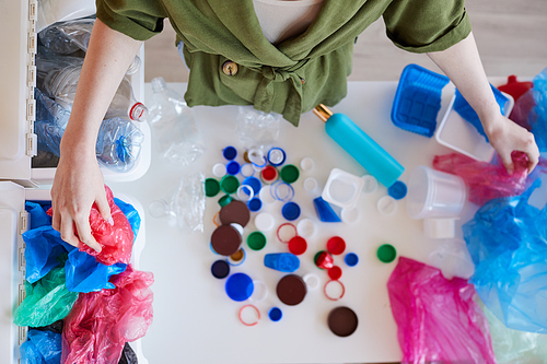 Top view background of unrecognizable woman sorting plastic waste at home before recycling, copy space