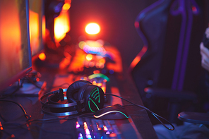 Close up of pro-gaming equipment on computer desk, focus on lit up headphones, copy space