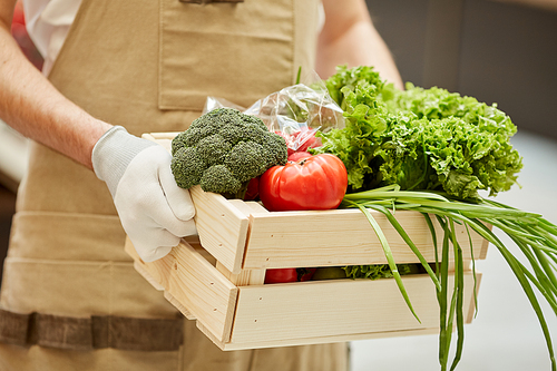 Close up of unrecognizable man holding box of vegetables while selling fresh produce at farmers market, copy space