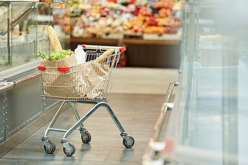 Background image of shopping cart with fresh groceries standing in supermarket isle, copy space