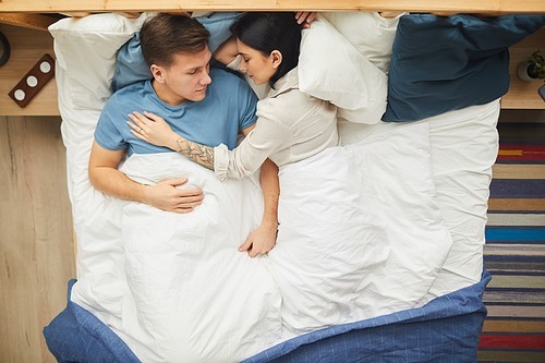 Top view portrait of modern young couple sleeping together on comfortable bed in blue and while covers, copy space
