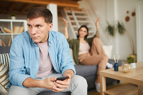 Portrait of modern couple fighting at home, focus on frustrated man in foreground, copy space