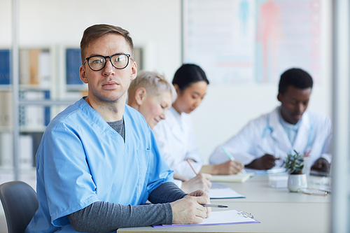 Portrait of mature male doctor  while sitting at table during medical council or conference in clinic, copy space