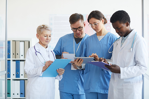 Waist up portrait of medics holding clipboards while standing in medical office interior, copy space