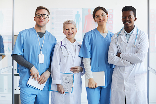 Waist up portrait of multi-ethnic group of doctors  while posing together in clinic interior