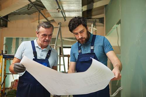 Portrait of father and son looking at floor plans while renovating house together, copy space