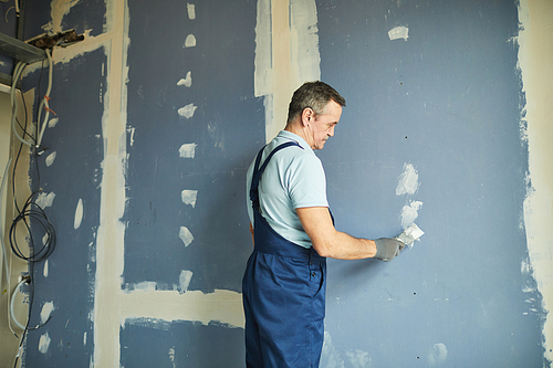 Portrait of senior man working on dry wall while renovating house, copy space