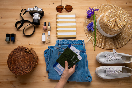 Unrecognizable woman putting passports with airline tickets on jeans while preparing for vacation