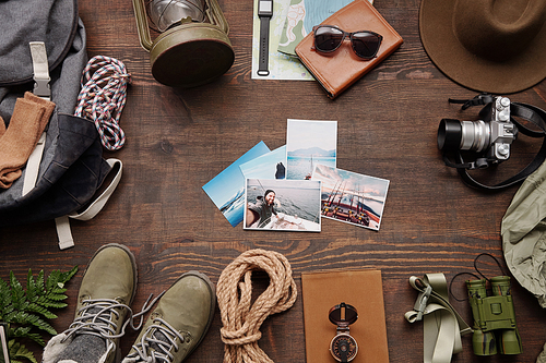 Above view of beautiful travel photos on wooden table with hiking stuff, planning new journey concept