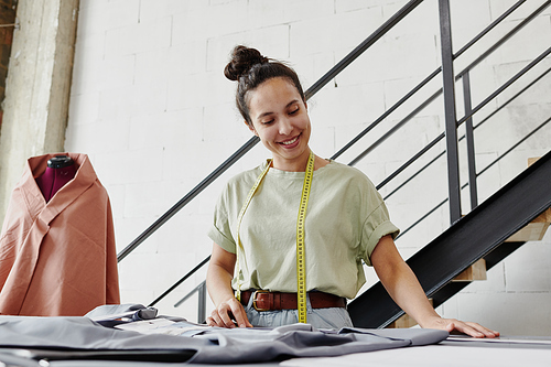 Young self-employed fashion designer or tailor looking through online sketches of seasonal collection items and choosing textile for models