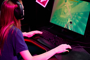 Young woman in headphones involved in video game playing videogame online in cybersports club