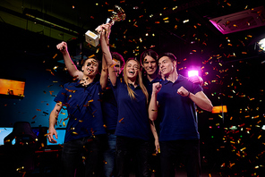 Five ecstatic young friendly video gamers expressing pride of their winning in cybersports competition while standing in falling confetti