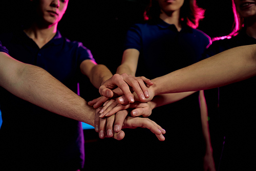 Close-up of young people stacking hands together while uniting to win game