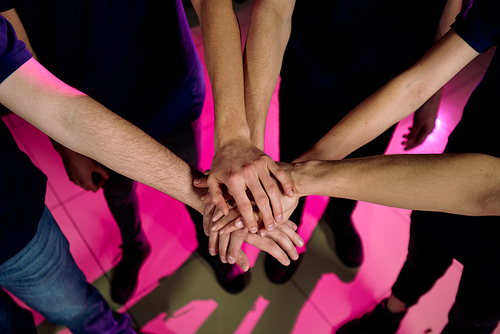 Above view of unrecognizable people standing in circle and stacking hands as symbol of teamwork