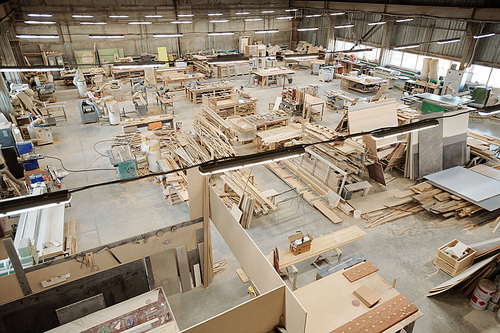 Interior of large workshop of contemporary furniture factory with workplaces consisting of workbenches with working supplies