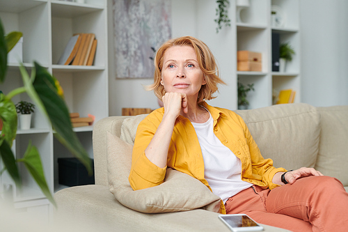 Blond pensive woman relaxing on couch in home environment while enjoying break in the middle of working day during quarantine