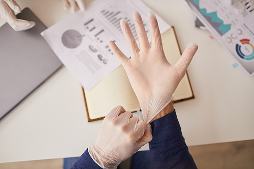 Top view close up of unrecognizable businessman putting on gloves during meeting in office, copy space