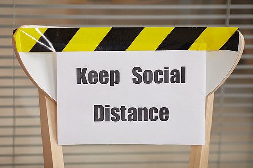 Background image of chair for waiting in line in office with Keep Social Distance sign, copy space