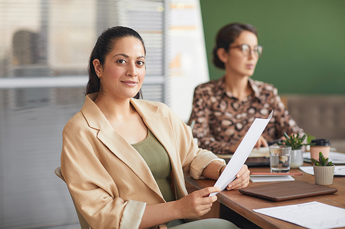 Portrait of successful contemporary businesswoman looking at camera during meeting with female business team, copy space