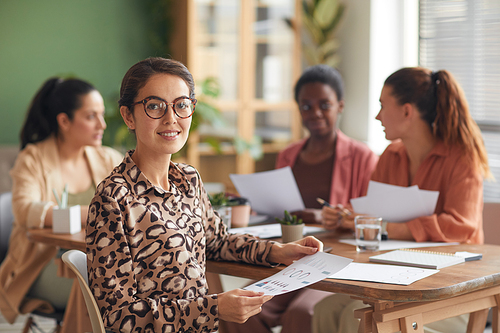 Portrait of elegant young businesswoman smiling at camera with female business team in background, copy space