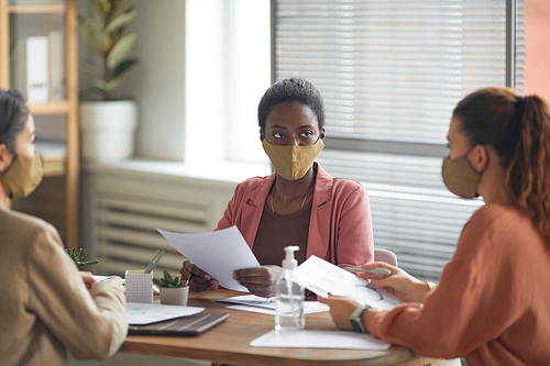 Portrait of young African-American businesswoman wearing mask while heading business meeting in office, copy space