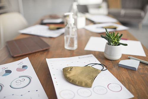 Close up background image of wooden meeting table with documents, masks and hand sanitizer in office, copy space