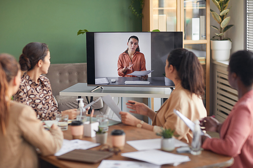 Portrait of businesswoman on computer screen talking to team during online business meeting in office, copy space